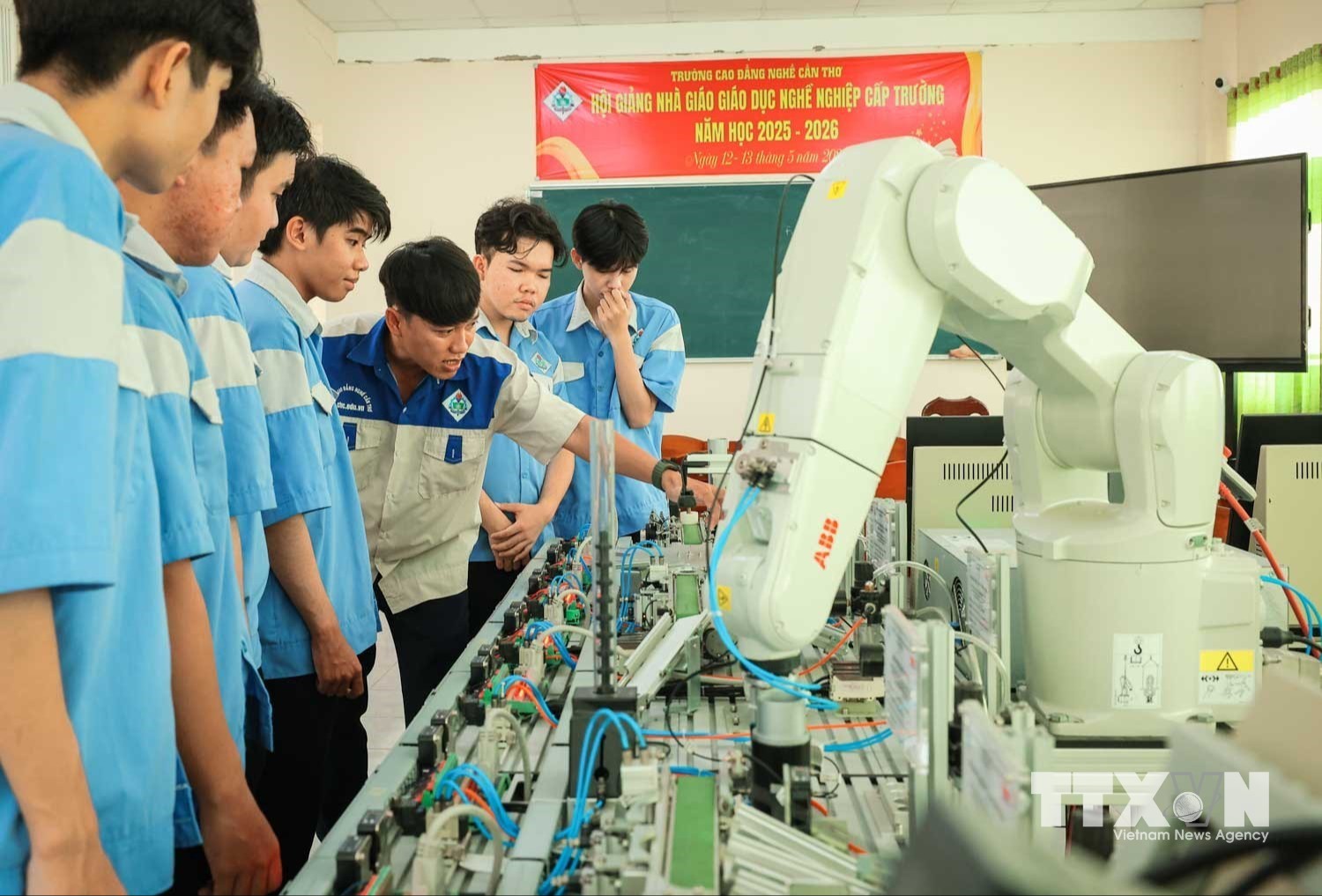 Thạc sĩ Nguyễn Tuấn Khanh – Giảng viên khoa Điện tử hướng dẫn sinh viên tìm hiểu thành phần các trạm điều khiển trong dây chuyền sản xuất linh hoạt, hiện đại, gắn với hoạt động điều khiển robot. (Ảnh: Hoàng Hiếu/TTXVN)